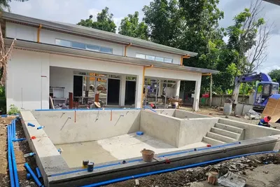 Single-storey house under construction with a swimming pool being built in front